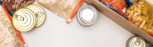 Preview: top view of cans and groats in zipper bags with wooden box on white background, food donation