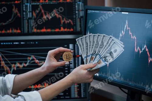 Preview: Woman's nd man's hand holding bitcoin and money in modern office with many monitors with graphs