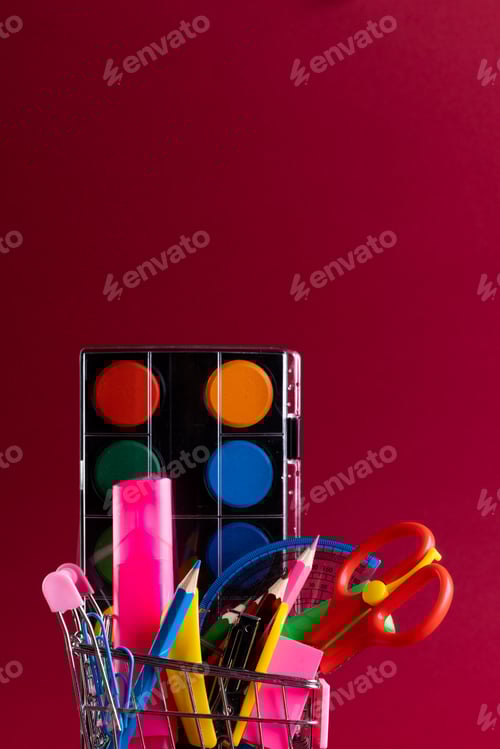 Visualização: Vista de perto do carrinho de compras em miniatura com materiais escolares e espaço de cópia em fundo vermelho
