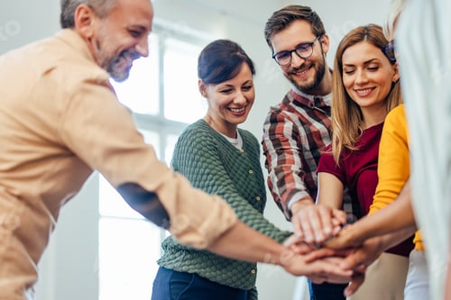 Preview: Group of Colleagues Smiling and Uniting Hands in Teamwork Gesture