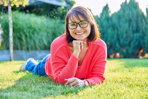 Preview: Outdoor portrait of smiling middle aged woman lying on grass