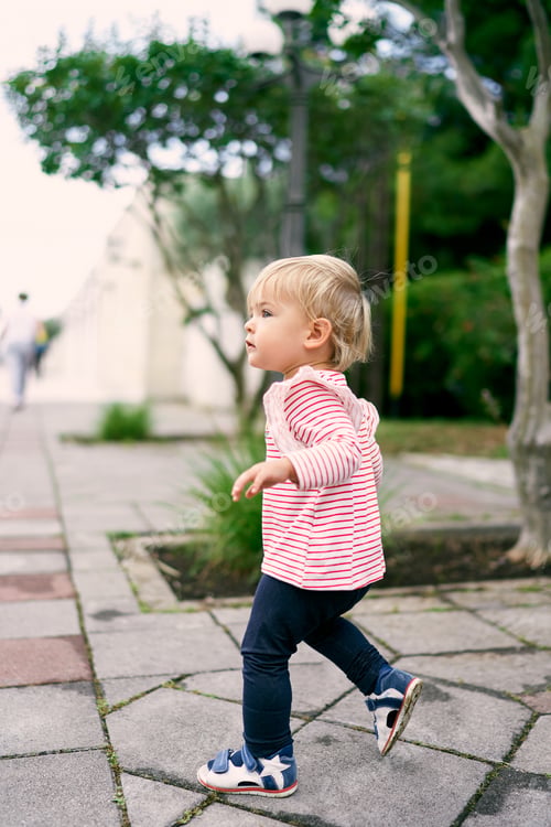 Preview: Little girl walking on a cobbled road in the park