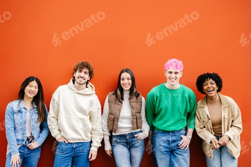 Preview: Happy multiracial young friends standing over isolated red urban background