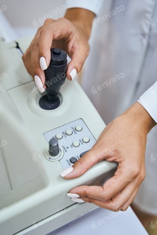Preview: Female optometrist using modern equipment in clinic