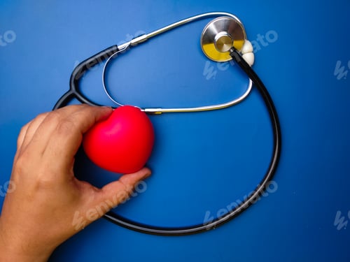 Preview: Hand holding red heart with statehoscop on blue background. Healthcare and medical concept.
