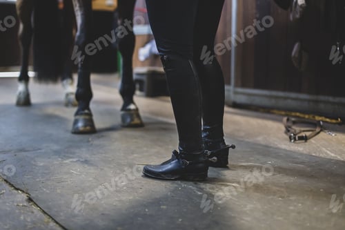 Preview: Feet of a horse trainer and hooves of a horse in a stable