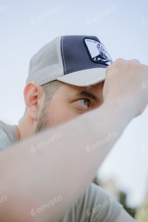 Preview: a man adjusts his cap, carefully looks ahead with one eye