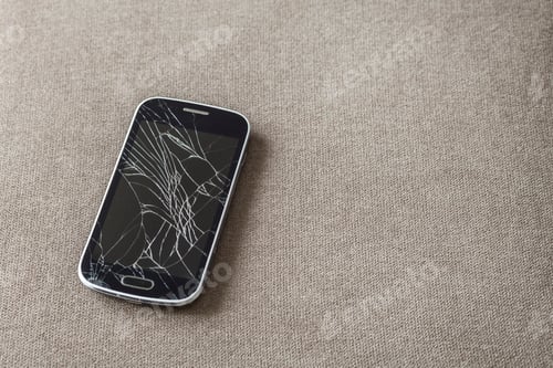 Preview: Black old cellphone with cracked screen on light cloth copy space background. Gadget repair and