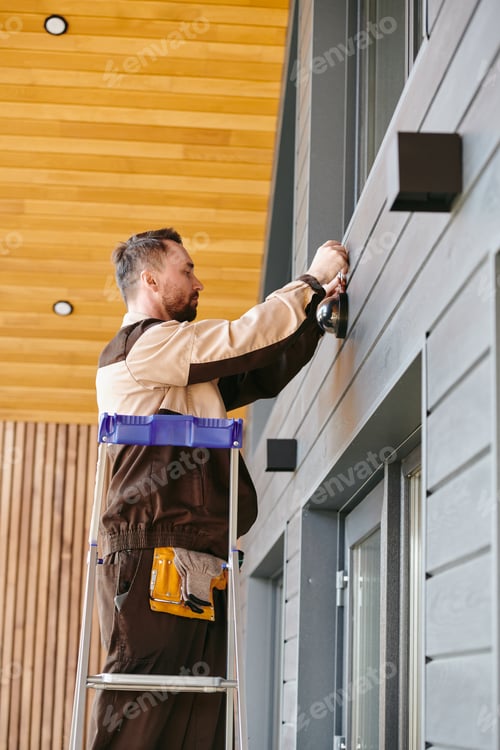 Preview: Young man fixing or repairing alarm system