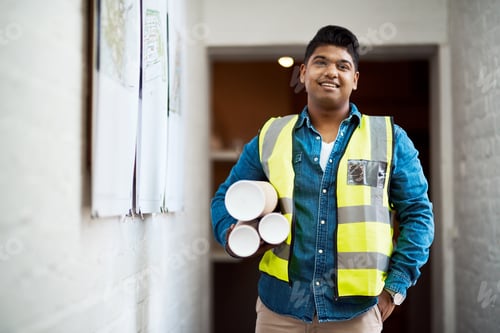 Preview: Shot of a young engineer holding blueprints on a construction site
