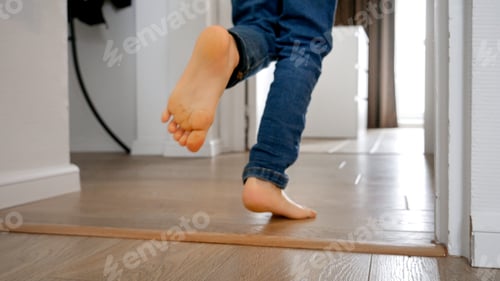 Preview: Little boy running down a long wooden corridor at home
