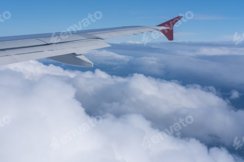 Preview: The view from window of plane on the wing of plane against background of fluffy clouds and blue sky