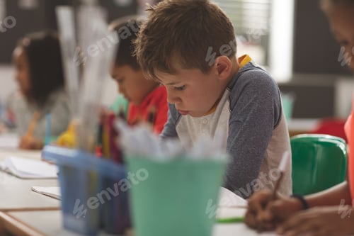 Preview: School boy writing a dictation on a notebook in a classroom