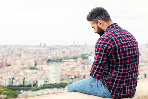 Preview: man sitting on the roof consulting the phone