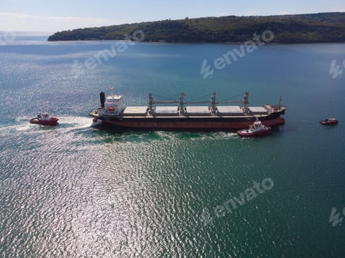 Preview: Aerial view of tug boat assisting big bulk carrier cargo ship. Large ship escorted by tugboat.