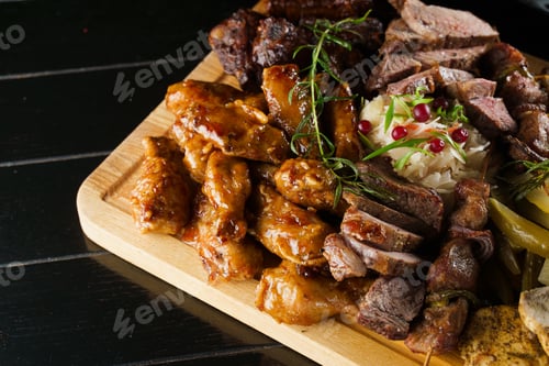 Preview: Juicy pork kebab with roasted potatoes and assorted sausages served on black plate.