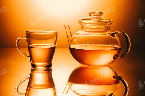 Preview: selective focus of cup of tea and teapot on orange background
