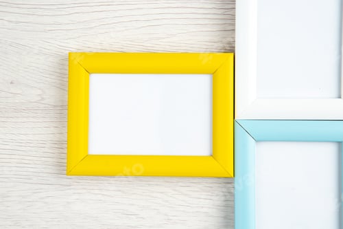 Preview: Overhead view of three empty picture frames in different colors on wooden stripped background