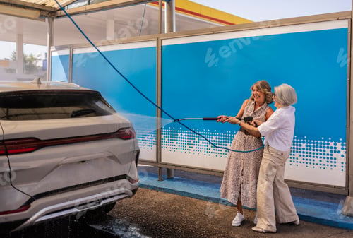 Preview: Senior women having fun washing car together