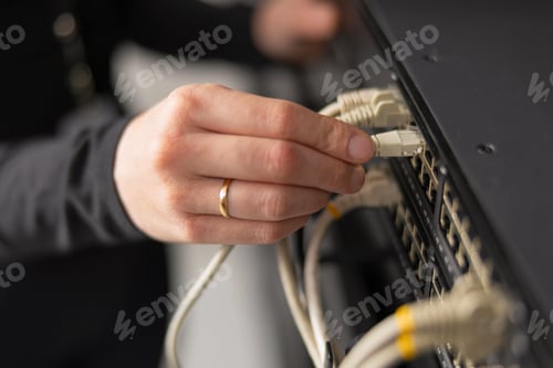 Preview: Adult IT technician setting up network cables in a data center and performing maintenance