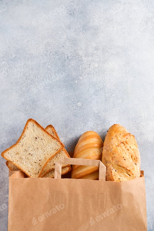 Preview: Mixed bread in a paper bag on light gray concrete stone table. Top view with copy space