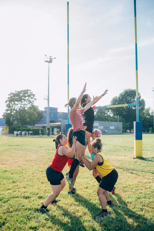 Preview: Group of friends playing a fun game of touch rugby at the park on a sunny day.