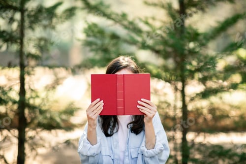 Preview: A person is holding a red hardcover book in front of their face
