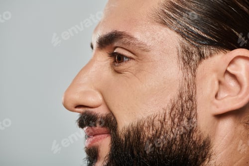 Preview: profile of cheerful arabic man with beard smiling and looking away on grey background
