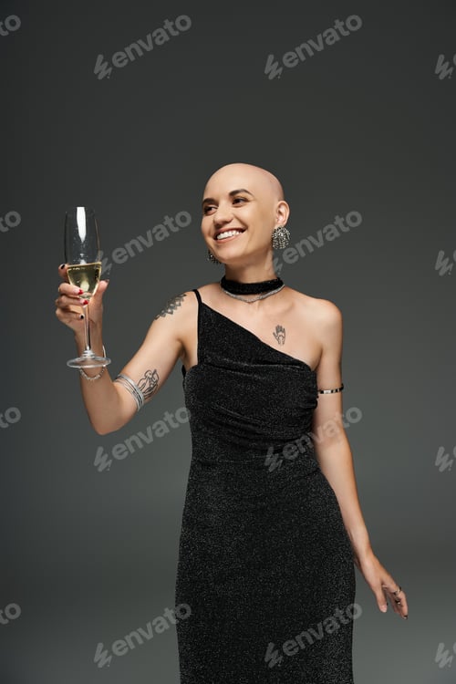 Preview: A radiant young bald woman celebrates in an elegant black dress, joyfully raising her glass