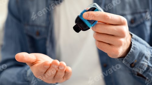 Preview: Young man pouring sanitizing gel on hands for disinfection