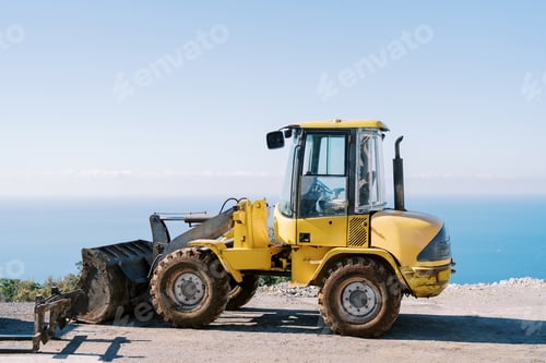 Preview: Yellow excavator stands on a steep seashore. Side view
