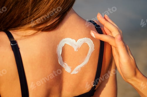 Preview: woman is applying sunscreen cream to a woman in a swimsuit on her back on the beach