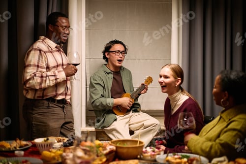 Preview: Diverse Young Adults Sharing Thanksgiving Dinner Laughing and Singing Together