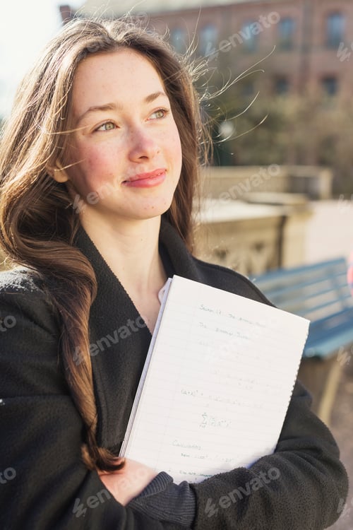 Preview: Beautiful teenage girl with book looking away outdoors