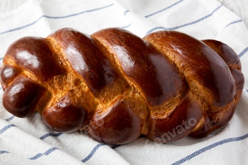 Preview: Homemade jewish challah bread on cloth, side view. Close-up.