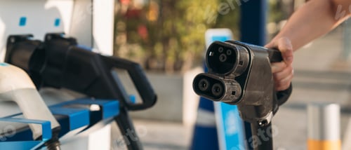 Preview: Close-up of hand plugging EV charger, clean energy concept.