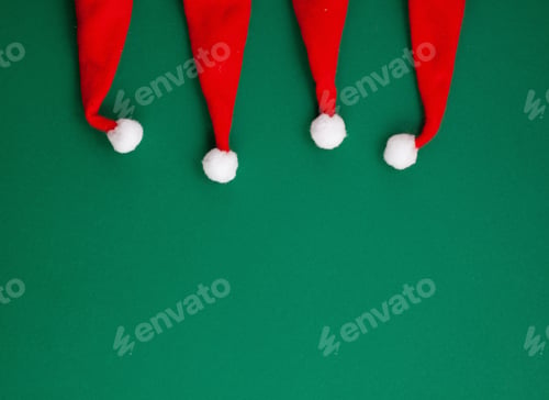Preview: Festive christmas decoration with red Santa hats over green background