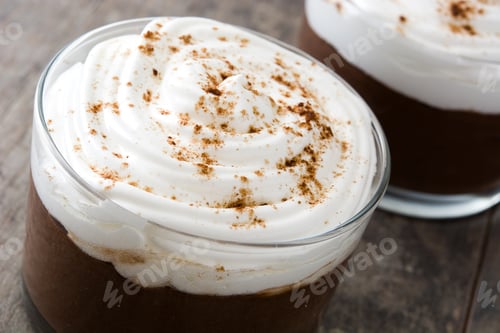 Preview: Delicious chocolate mousse topped with whipped cream and cinnamon on rustic wooden table