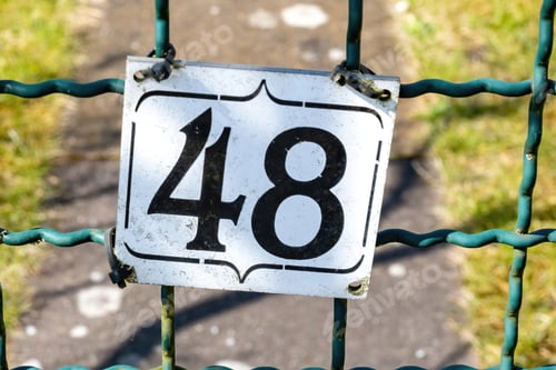 Preview: Closeup shot of a number plate on the fence with the number 48