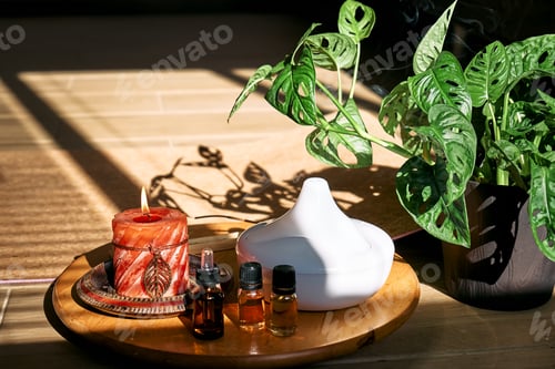 Visualização: Difusor de óleo essencial, vela acesa, diferentes tipos de óleos e essências perto do tapete de ioga.