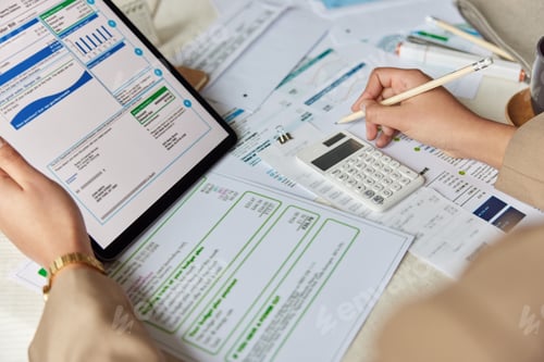 Preview: Unrecognizable female worker counts budget on calculator reviews receipts and bills finds profit