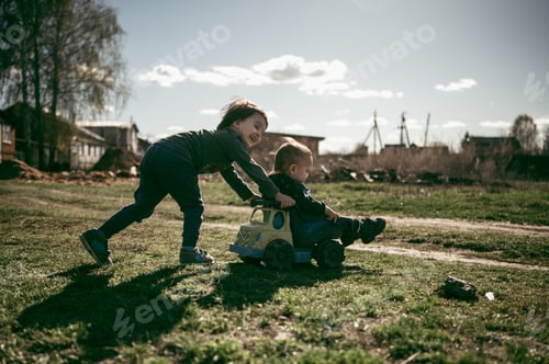 Preview: The boy rides his younger brother's toy car. Summer in the village