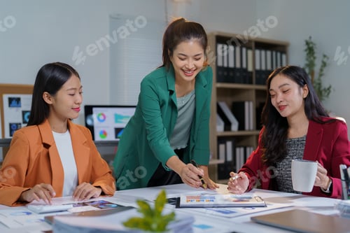 Preview: Three asian businesswomen are discussing financial charts and analyzing statistical graphs while wor