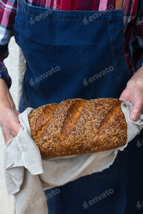 Preview: Fresh loaf of homemade rye bread in woman hands