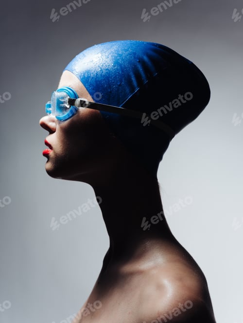 Preview: Side view of a woman in a blue swimming cap and glasses on a gray background