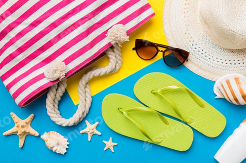 Preview: Beach accessories straw hat and seashell on colored table. Summer concept background