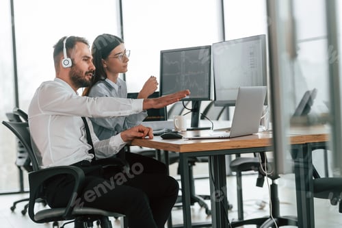 Preview: Man is in headphones. Two employees are working in the office together