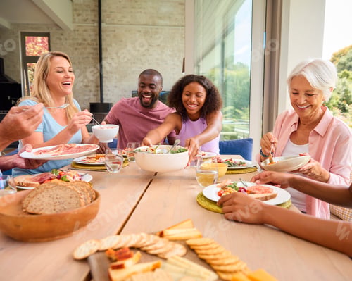 Preview: Three Generation Family Indoors Around Table At Home Serving And Eating Meal Together