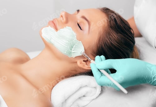 Preview: Beautician putting facial mask with algae extract to a woman