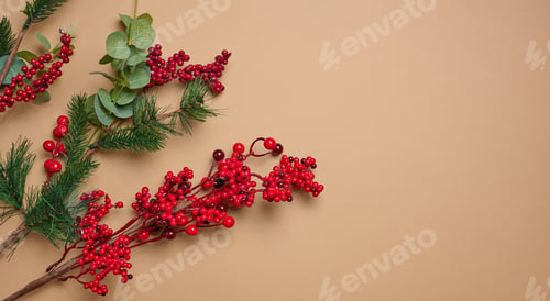 Preview: Decorative Christmas branch with red berries and pine cones on a brown background, top view
